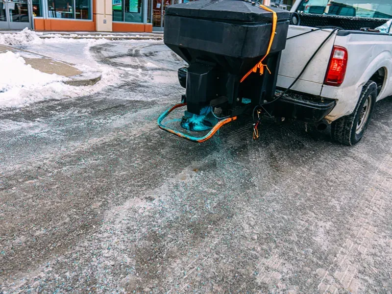 Truck spreader applying ice melt to an icy surface